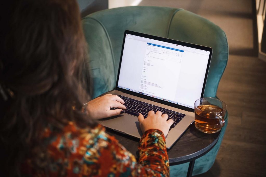 Jeanette Niemi skriver ett mejl på en laptop med en tekopp bredvid sig